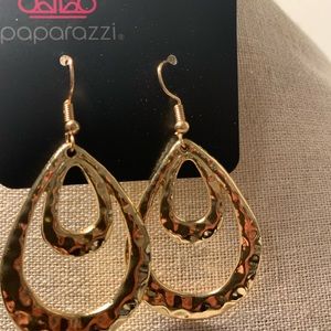 Shinny hammered gold teardrop shaped earrings .
